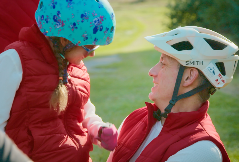 Caregiver adjusting a child's helmet before adaptive biking