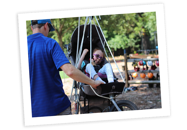 Caregiver assists a child with Rett syndrome on an adaptive swing