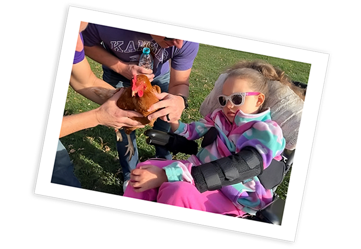 Child with Rett syndrome receives support during an outdoor activity