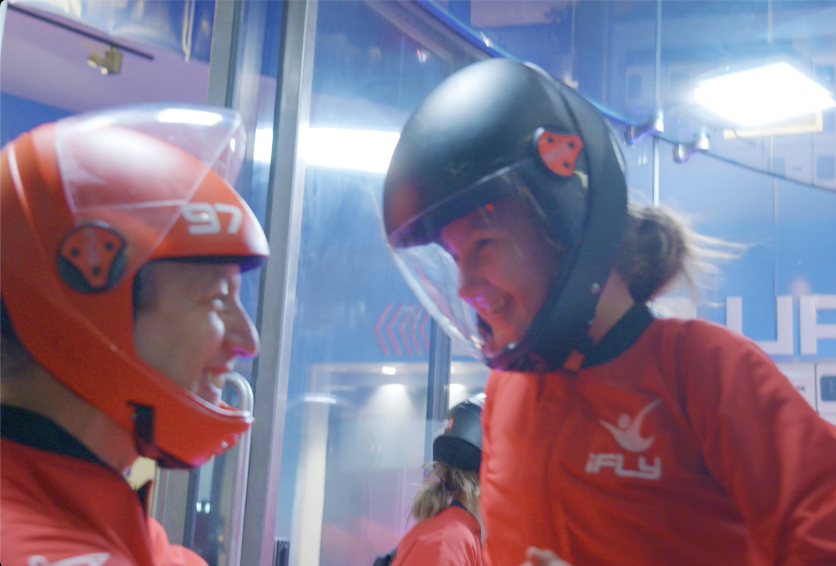 Instructor talking with a child wearing a helmet before adaptive indoor skydiving